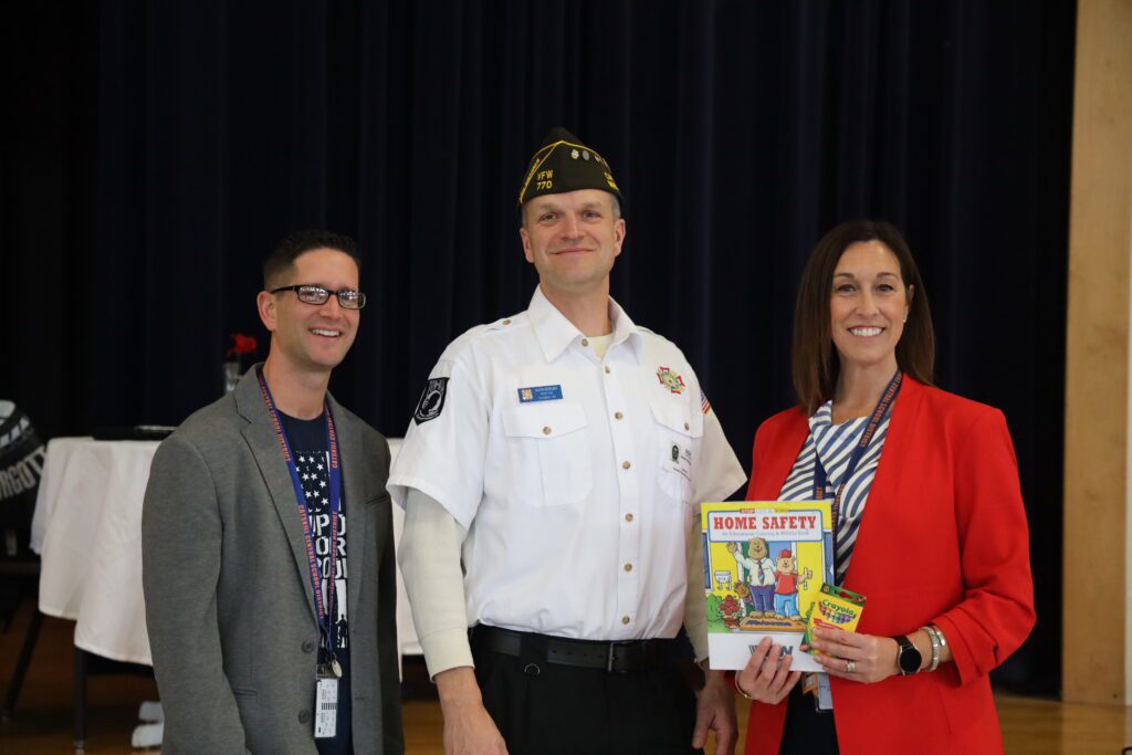 man, woman, and veteran pose with patriotic coloring book.