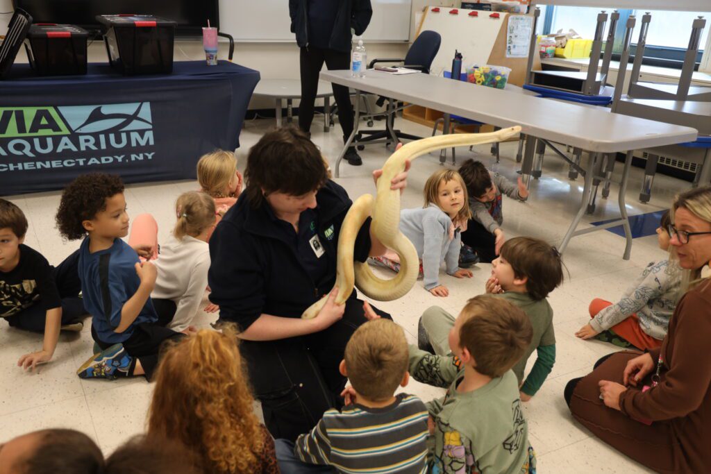 woman showing snake to young students