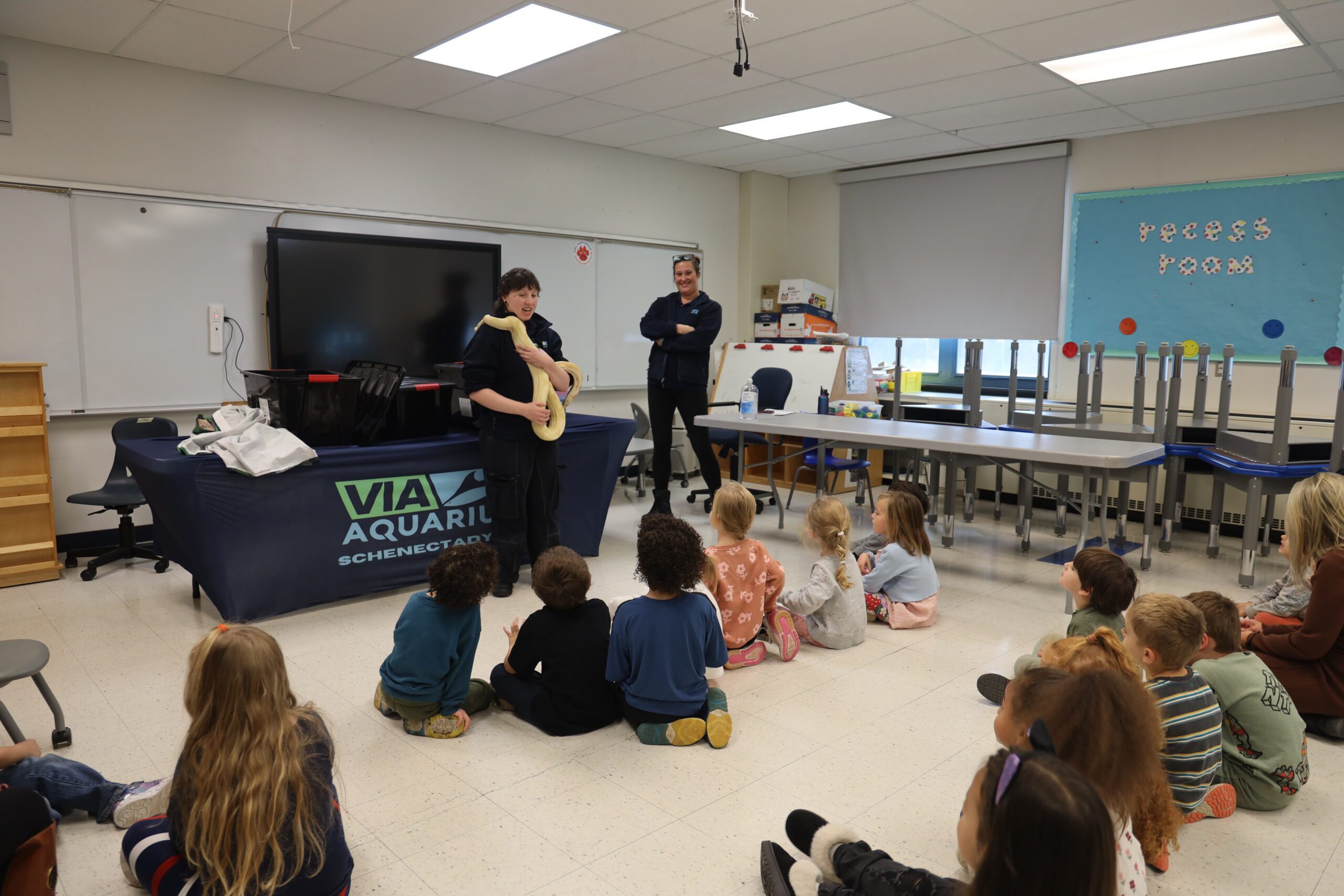 woman showing snake to young students