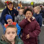 woman wearing turkey hat standing with group of students.