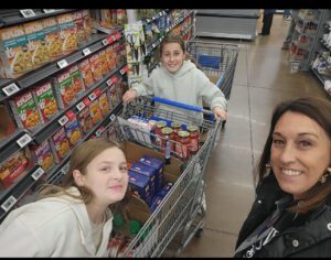 Woman and two girls shopping in grocery store.