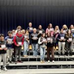 2025 Fall Sports Awardees standing on bleachers holding certificates