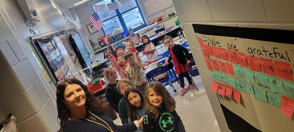 students pose near wall with gratitude portraits