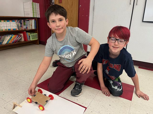 two boys posing with miniature wheeled cart