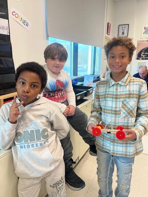 three boys posing with miniature wheeled cart