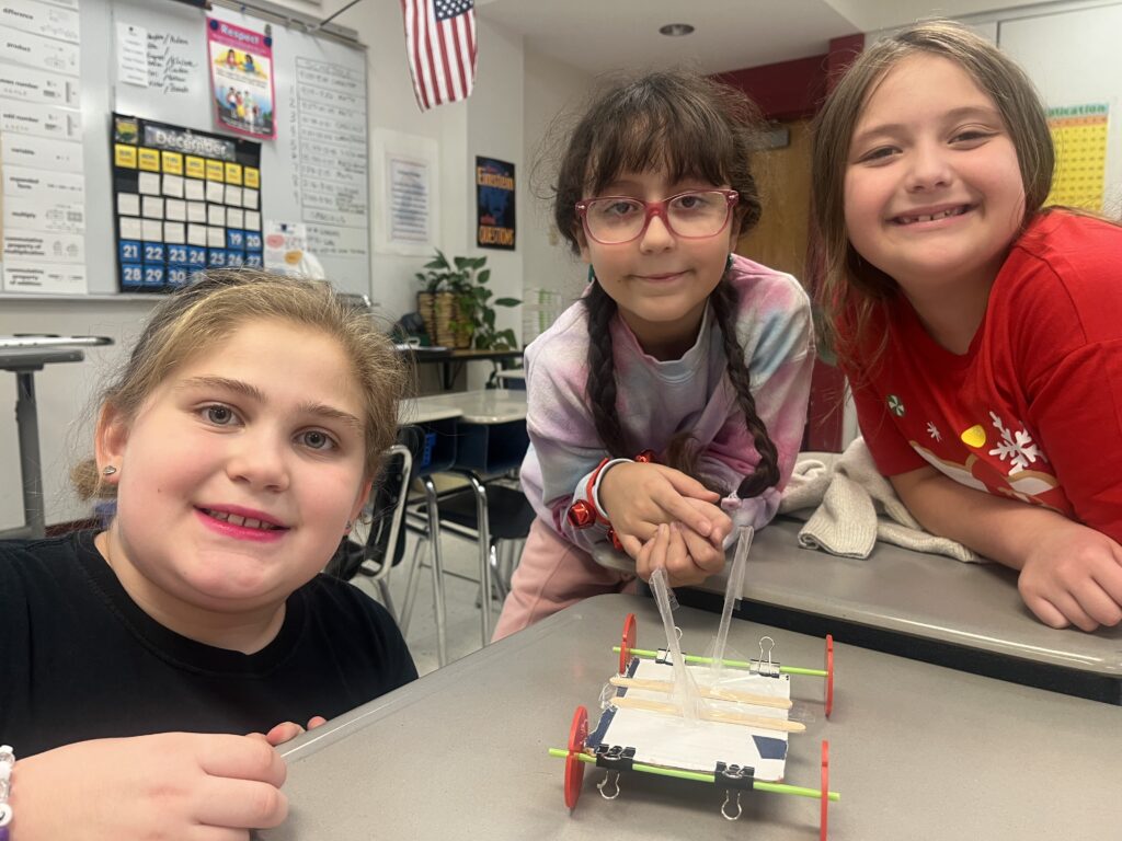 three girls posing with miniature wheeled cart