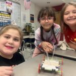 three girls posing with miniature wheeled cart