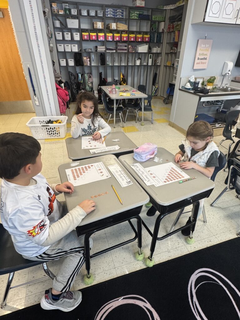 students lloking at coins on their desks