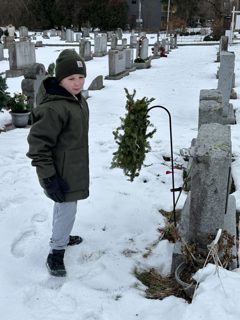 boy laying wreath on veterans' graves
