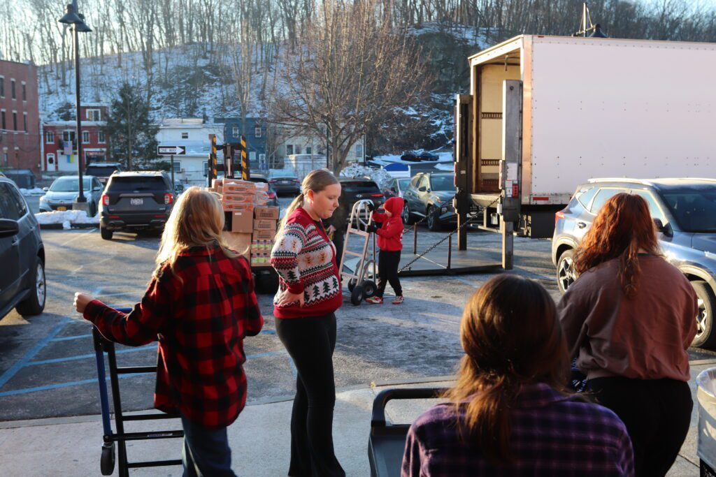 teenage girls and boy and adults loading boxes onto truck