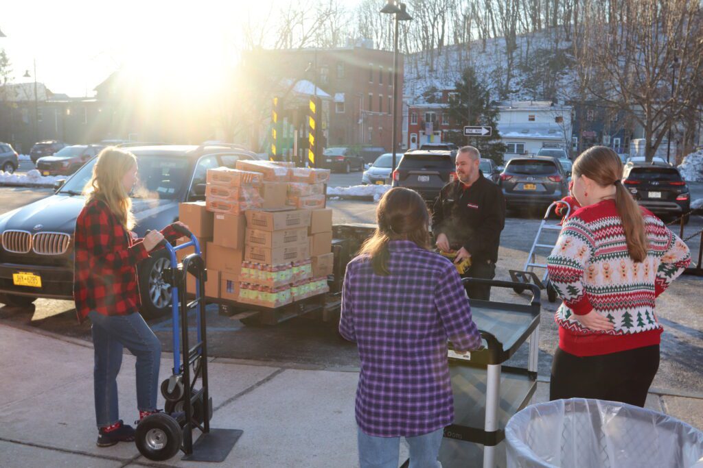 teenage girls and boy and adults loading boxes onto truck