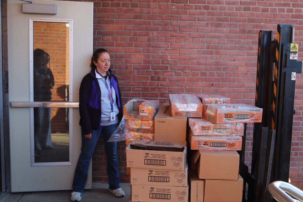 woman standing next to pallet of boxes