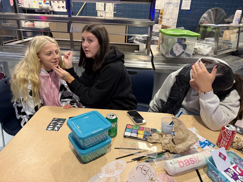 teenage girl painting middle school age girl's face