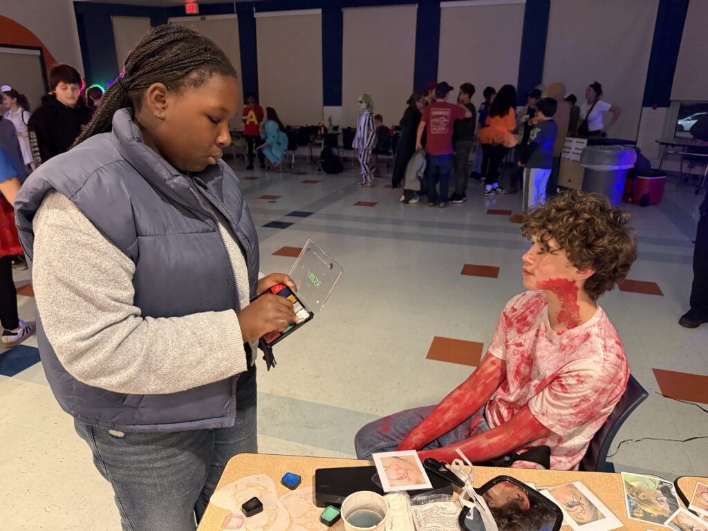 teenage girl painting middle school age boys's face