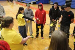 students holding strings that all connect to one girl in a yellow shirt