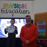 boy holding certificate next to man