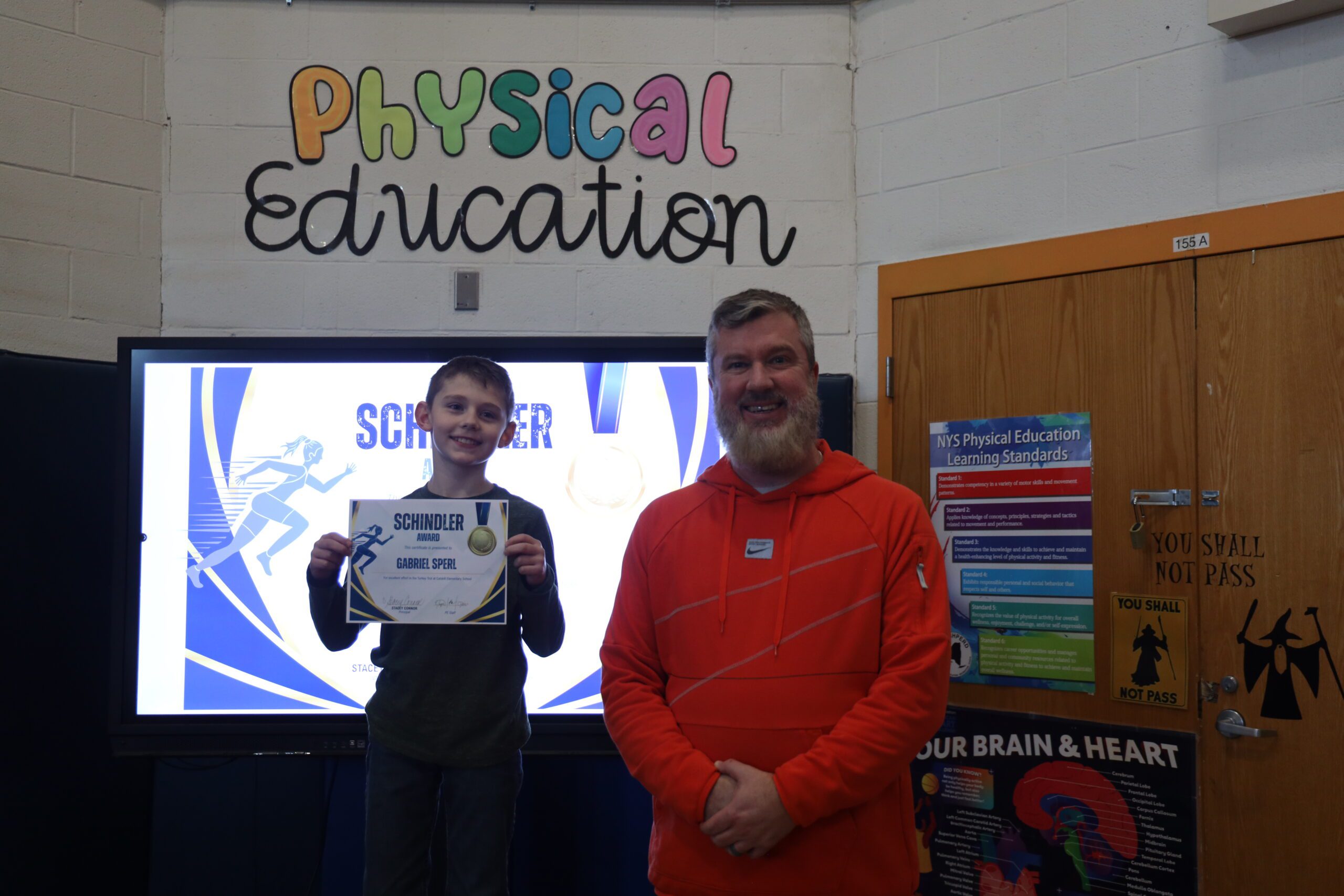 boy holding certificate next to man