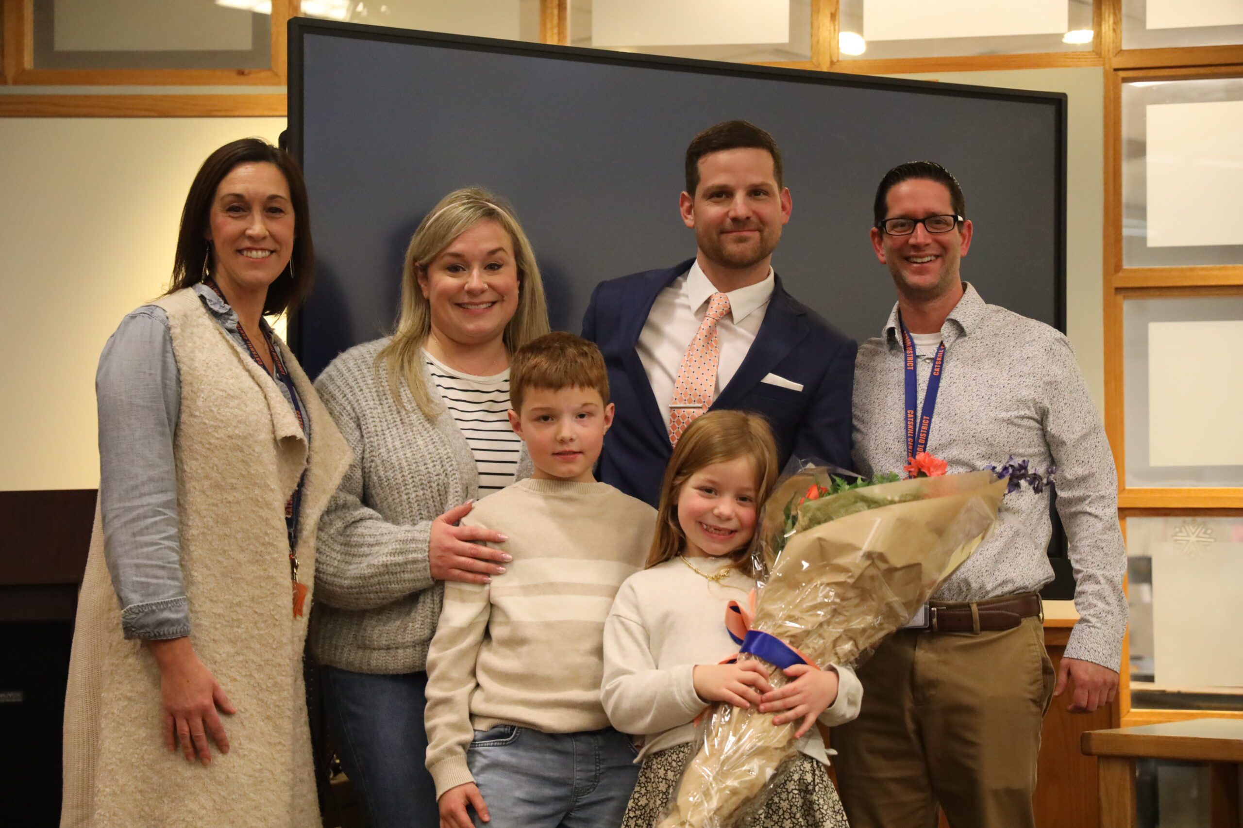 man poses with family and admistrators