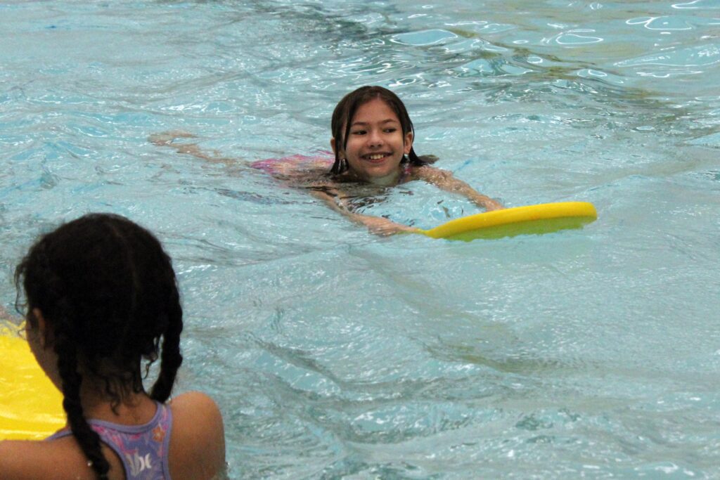 girl swimming with kickboard