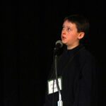 boy spelling at microphone on stage