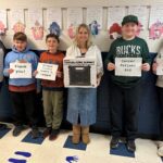 students and teachers holding thank you notes and large travel speaker