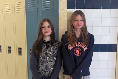Two girls smiling in front of hallway lockers