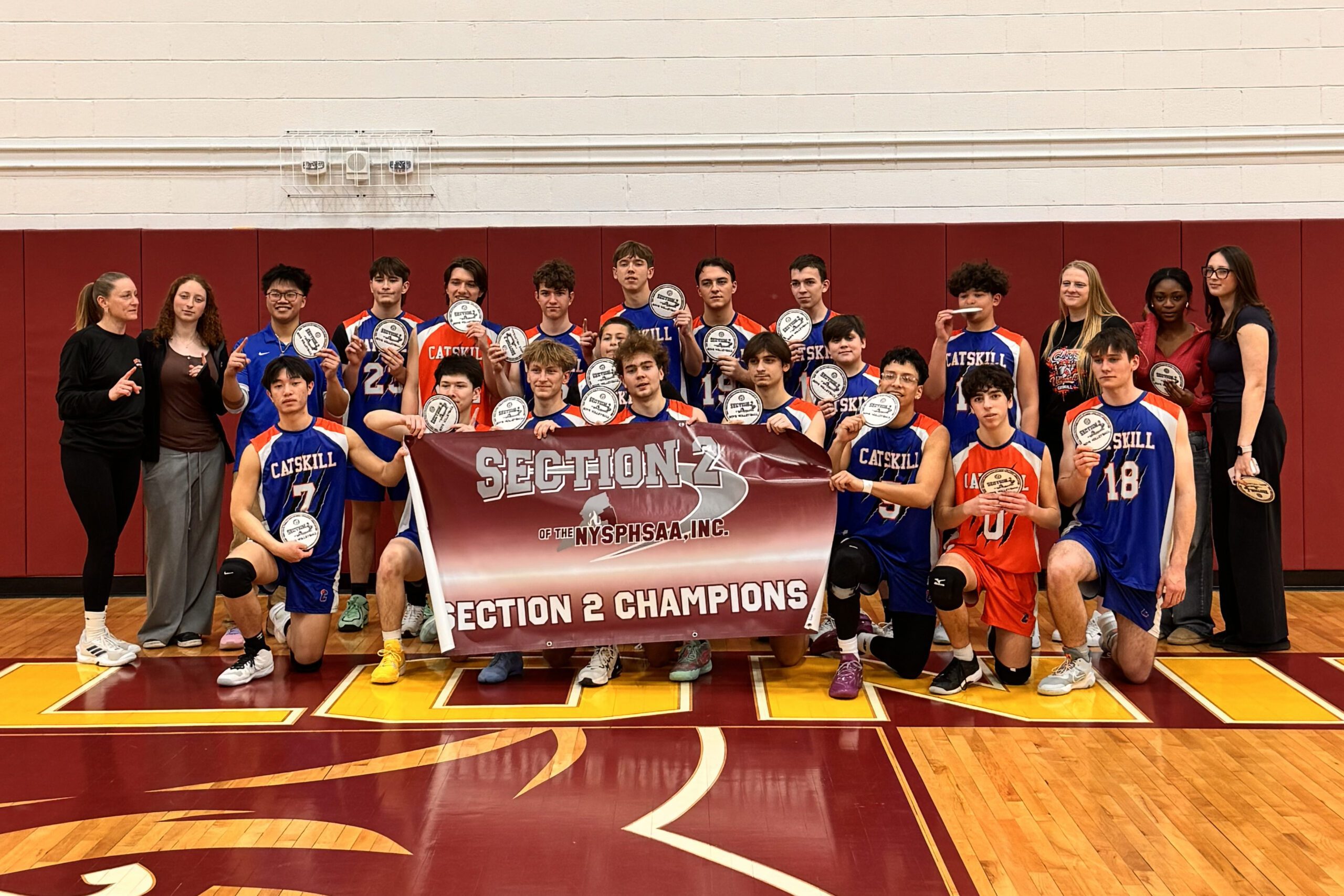 Boys volleyball team holding Section 2 Championship banner