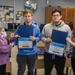 two women handing award certificates to two young men