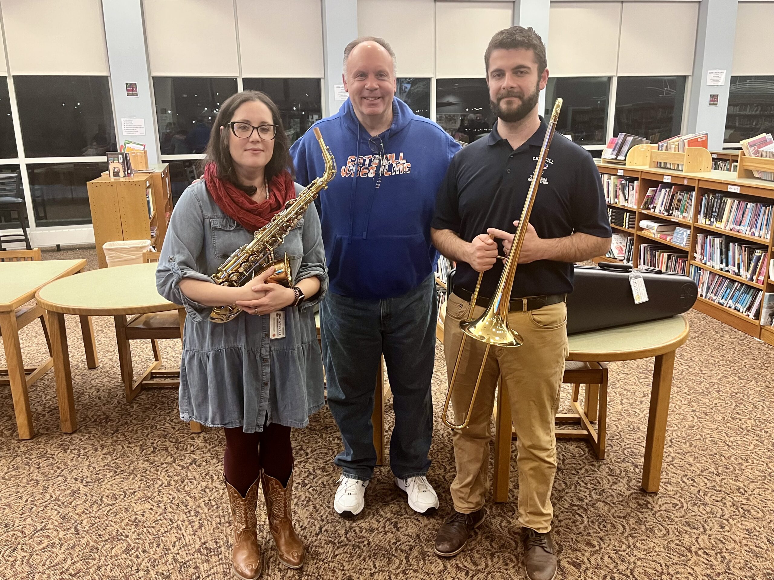 man flanked by woman and man holding band instruments
