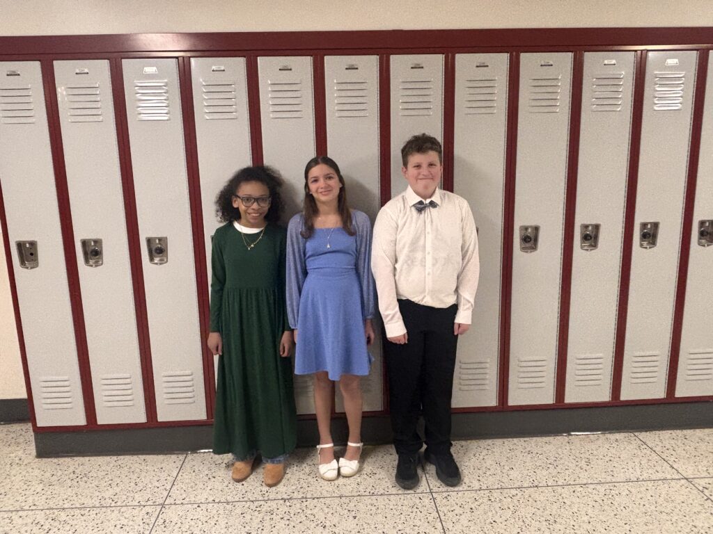 two girls and boy pose for photo in front of lockers