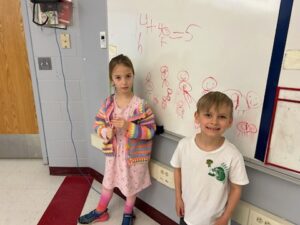two students doing math problem on whiteboard