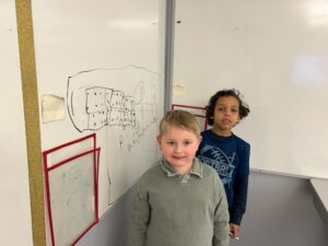 two students doing math problem on whiteboard