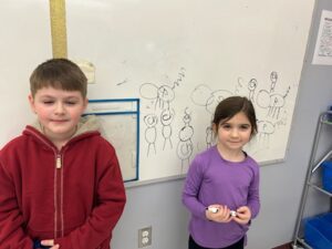 two students doing math problem on whiteboard