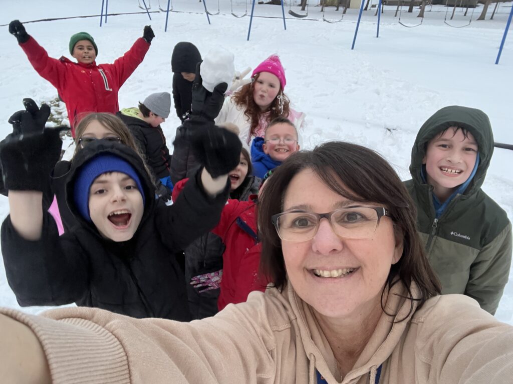 woman taking selfie with group of students outside in snow