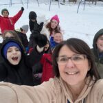 woman taking selfie with group of students outside in snow