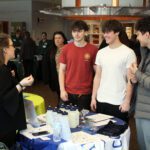 three boys talk with woman at job booth