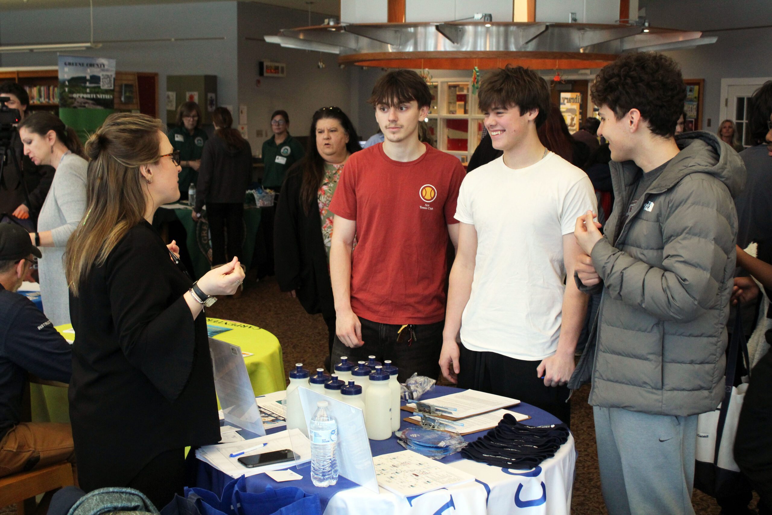 three boys talk with woman at job booth 