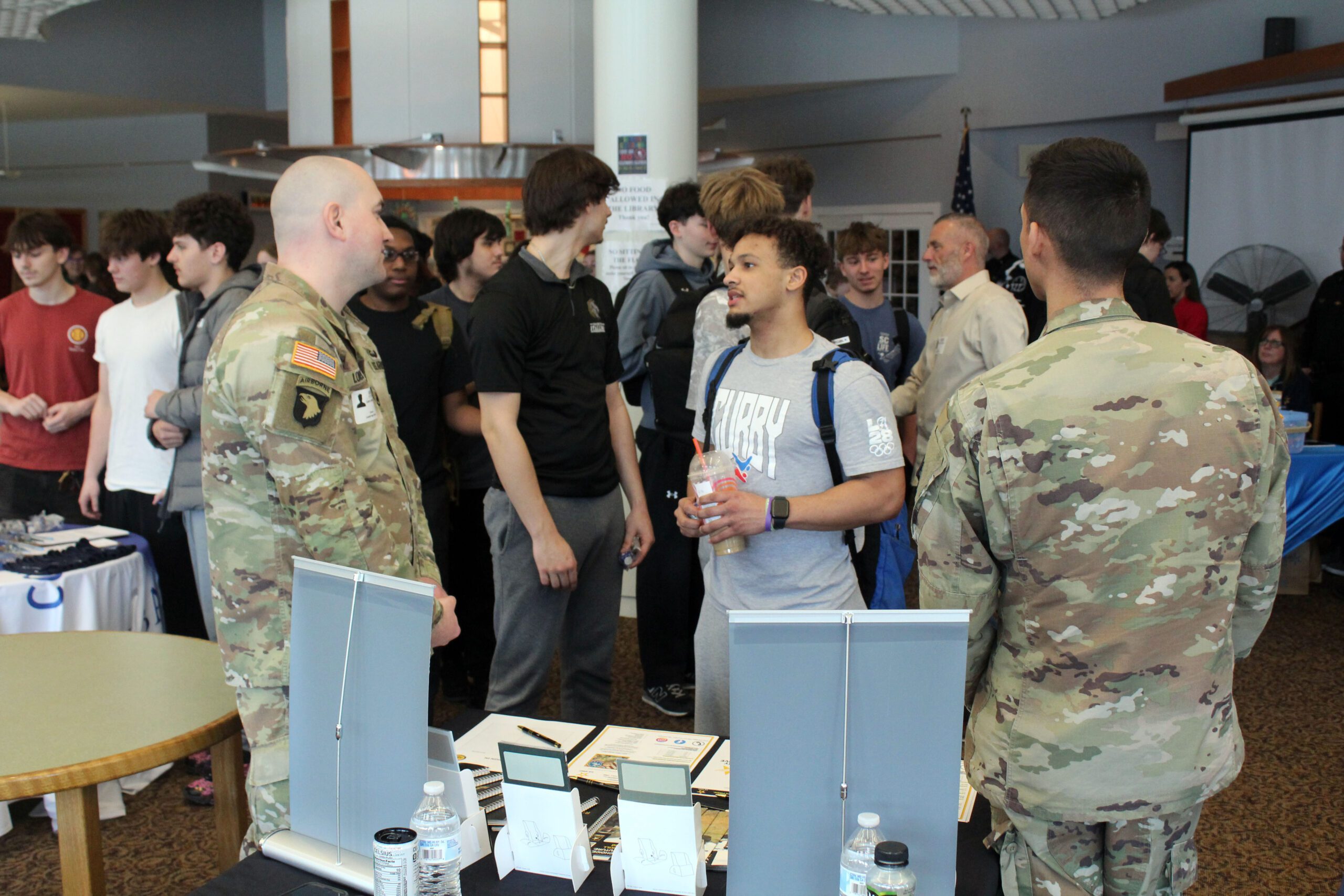 young man talks to two Army recruiters