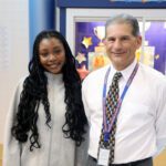 smiling man standing next to smiling teenage girl