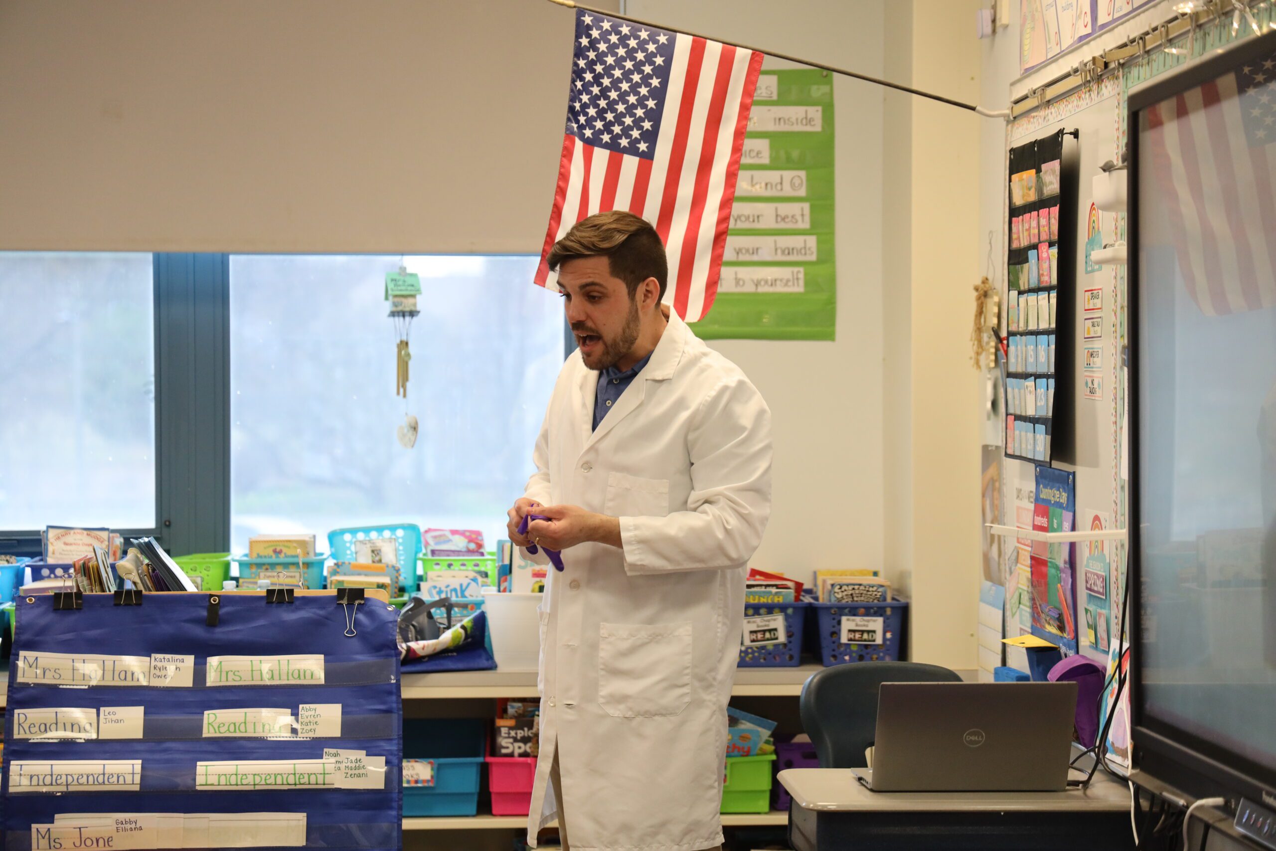 man wearing white lab coat giving job presentation in classroom