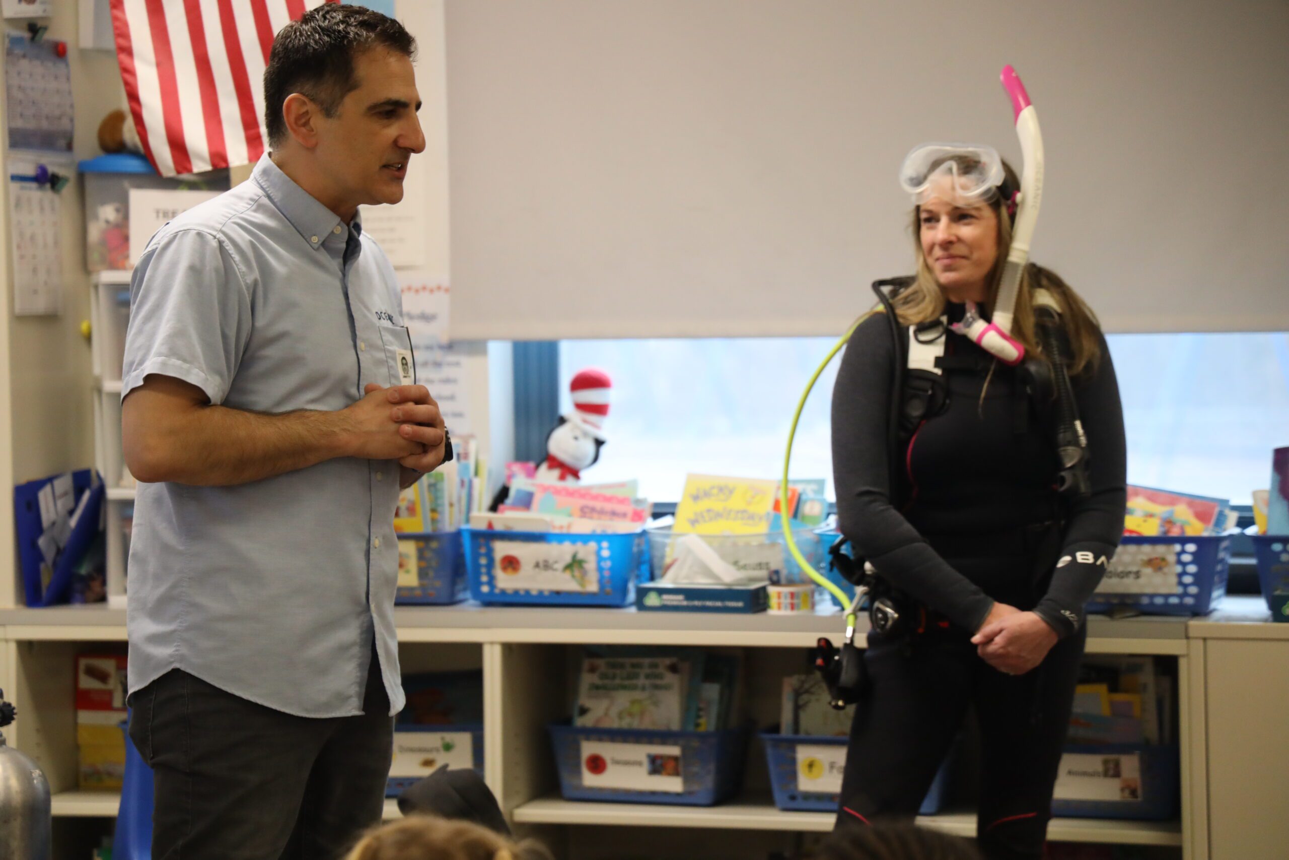 man and woman dressed in SCUBA gear giving presentation in classroom