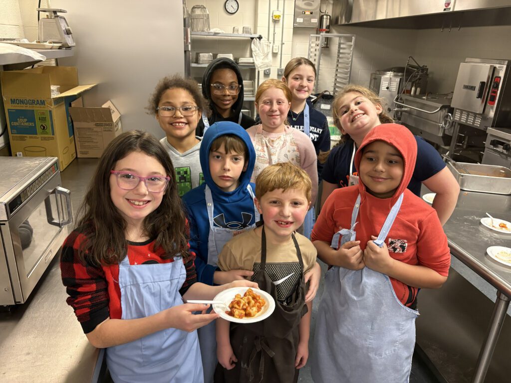 students pose for group photo with food they made