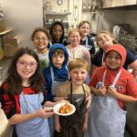 students pose for group photo with food they made