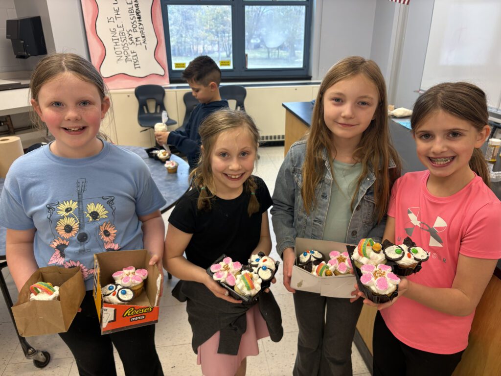 students pose for group photo with cupcakes they made