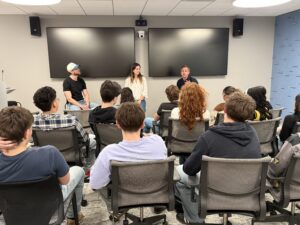 panel of young professionals talking to group of seated students