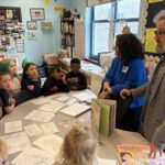 man and woman giving job presentation to students gathered around a table