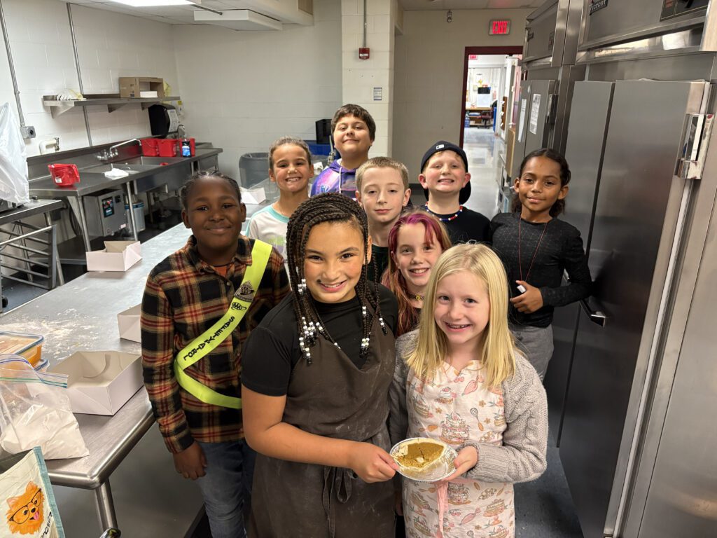 students pose for group photo with food they made