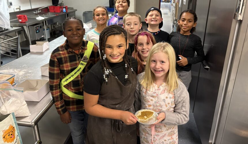 students pose for group photo with food they made
