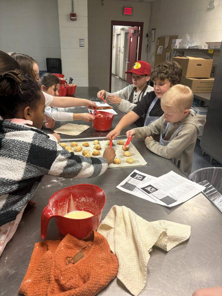 student putting dough balls on cookie sheets