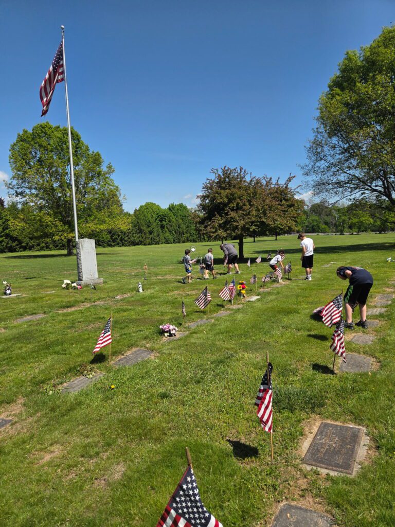 students placing flags in cemetery